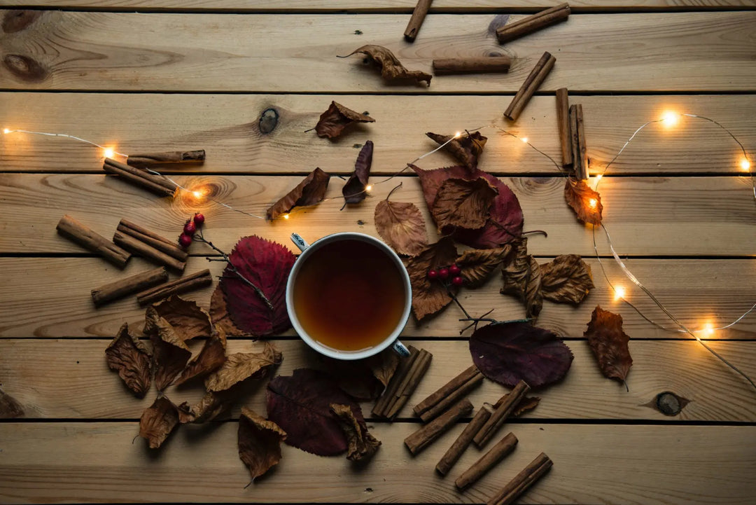 Eine Tasse heißer Kräutertee, umgeben von Herbstblättern.